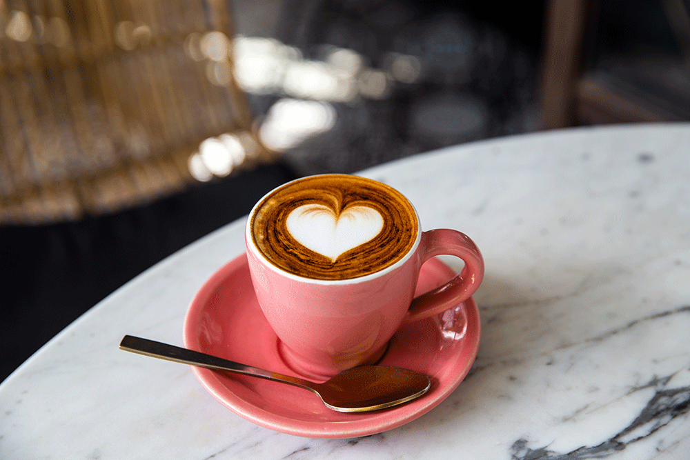 Tina Tschage Background, rote Kaffeetasse auf einem Bistrotisch mit Herzchen auf dem Milchschaum